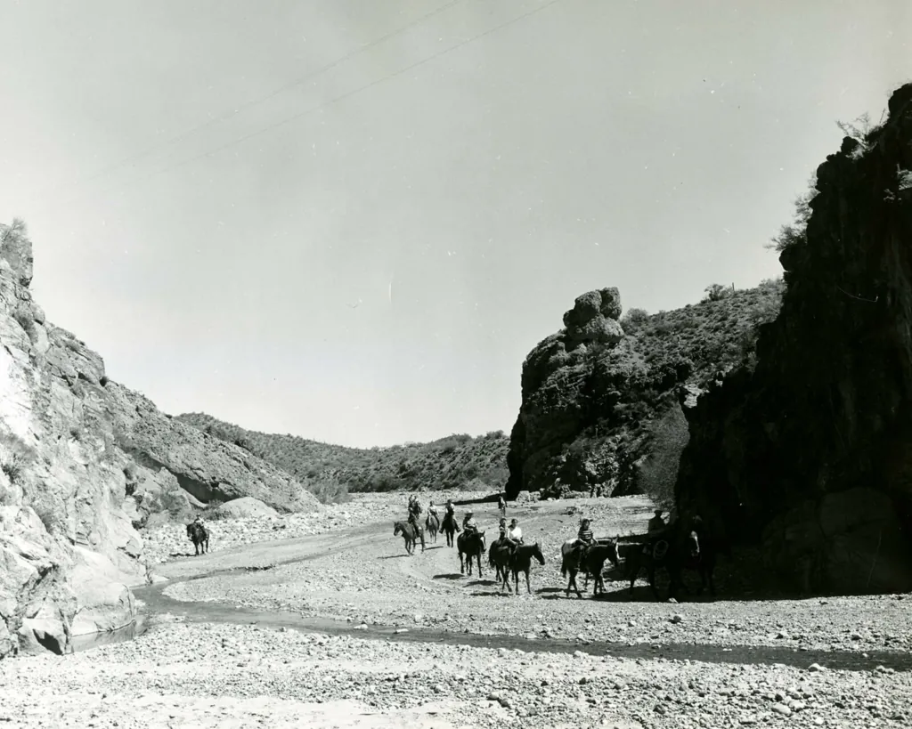 A black and white photo showing guests on a horseback ride through the mountains near Castle Hot Springs