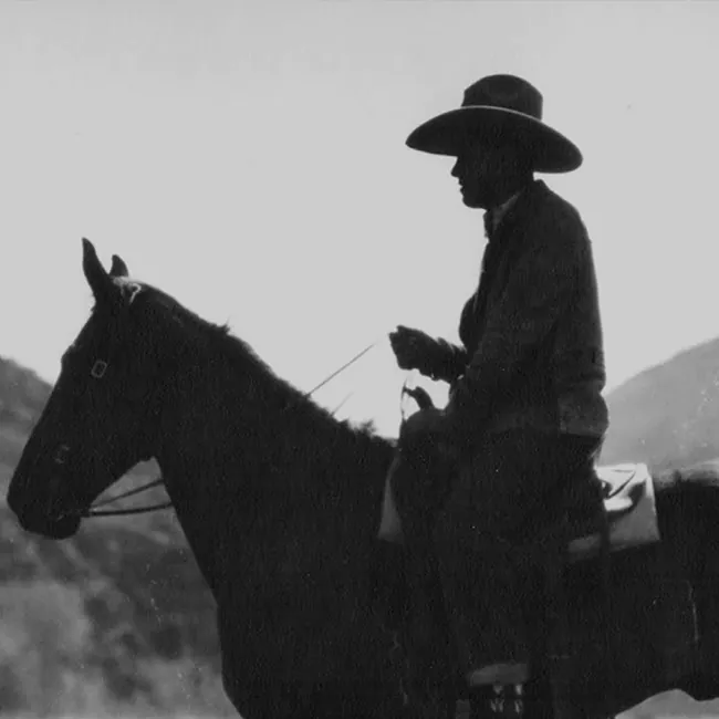 Black and white photo of a cowboy on a horse.