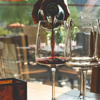 Hand Pouring Red Wine Into Polished Wine Glasses