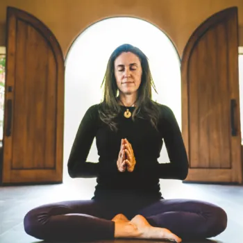 Woman Meditating Inside Naturally-Lit Lodge