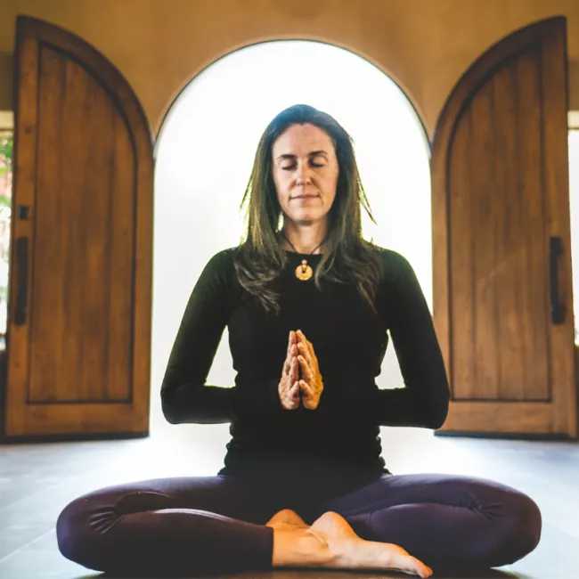 Woman Meditating Inside Naturally-Lit Lodge