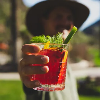 Man Handing a Tropical Pink Cocktail Topped with Fresh Dill