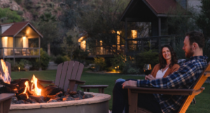 During a romantic getaway in Arizona, a couple sip wine while sitting in chairs by an outdoor firepit.