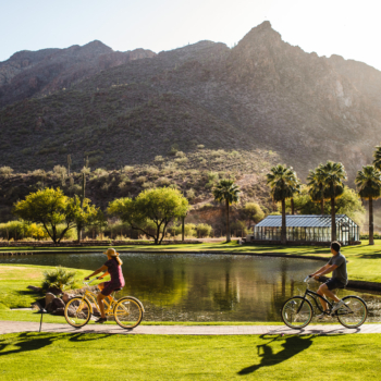 A couple biking through the grounds of a inclusive hot springs resort