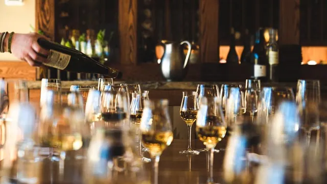 Table of wine glasses and pouring of wine bottle for a wine tasting class