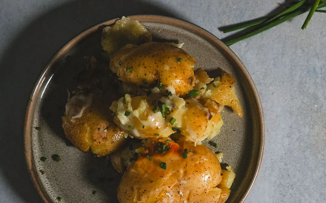 " An overhead view of cooked cast iron potatoes, garnished with fresh greens."
