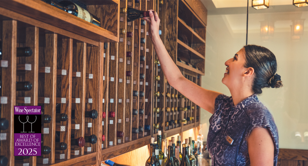 Sarah Foote, Director of Wine and Service at Harvest, pulling a bottle of wine from the wine cellar 
