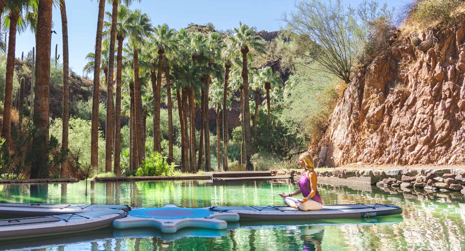A woman meditating on a paddleboard during yoga at Castle Hot Springs.