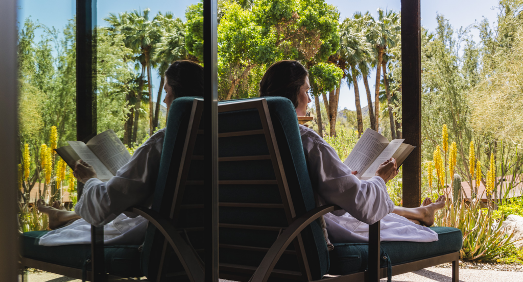 A woman reading on a lounger on the patio of her private Spring Bungalow