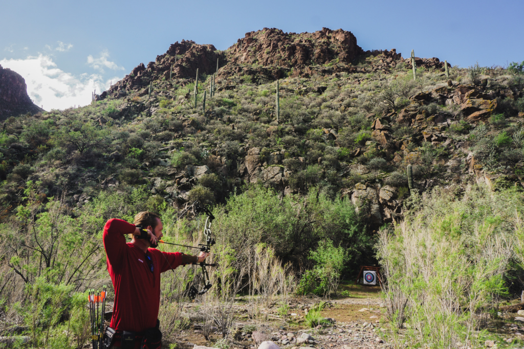 Man Practicing Archery with Mountains and Target