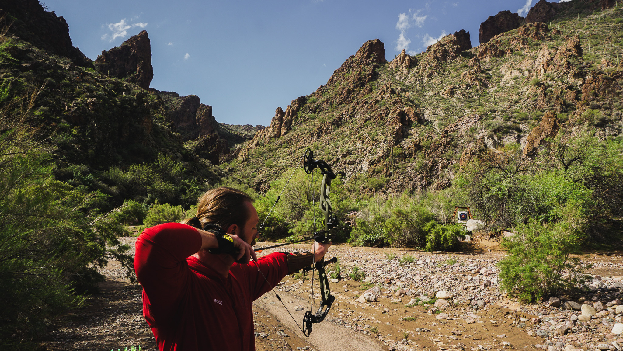 Man Practicing Archery with Mountains and Target