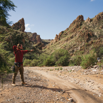 Man Practicing Archery with Mountains and Target