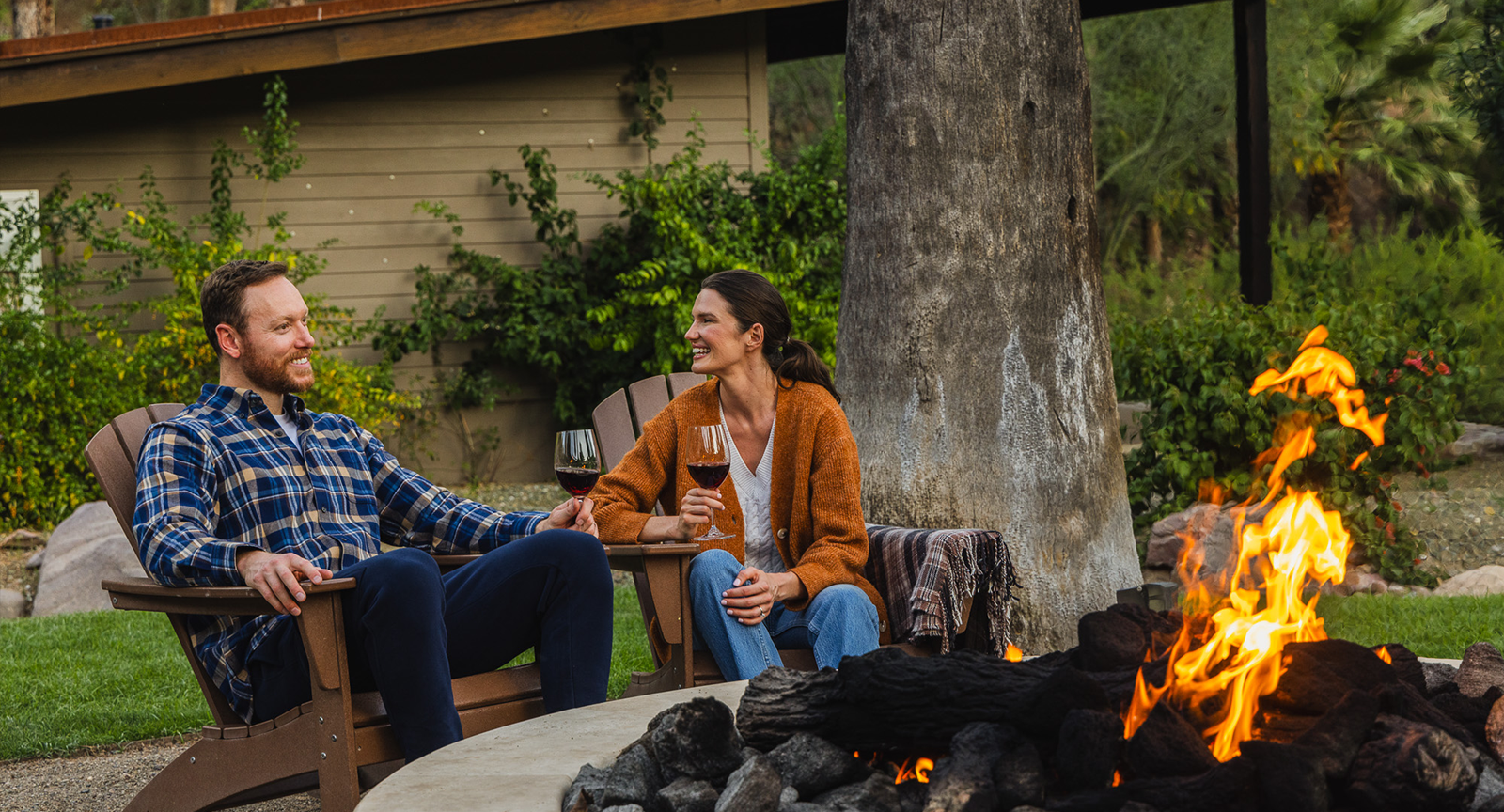 A man and woman enjoying a glass of wine by the firepit at Castle Hot Springs resort.