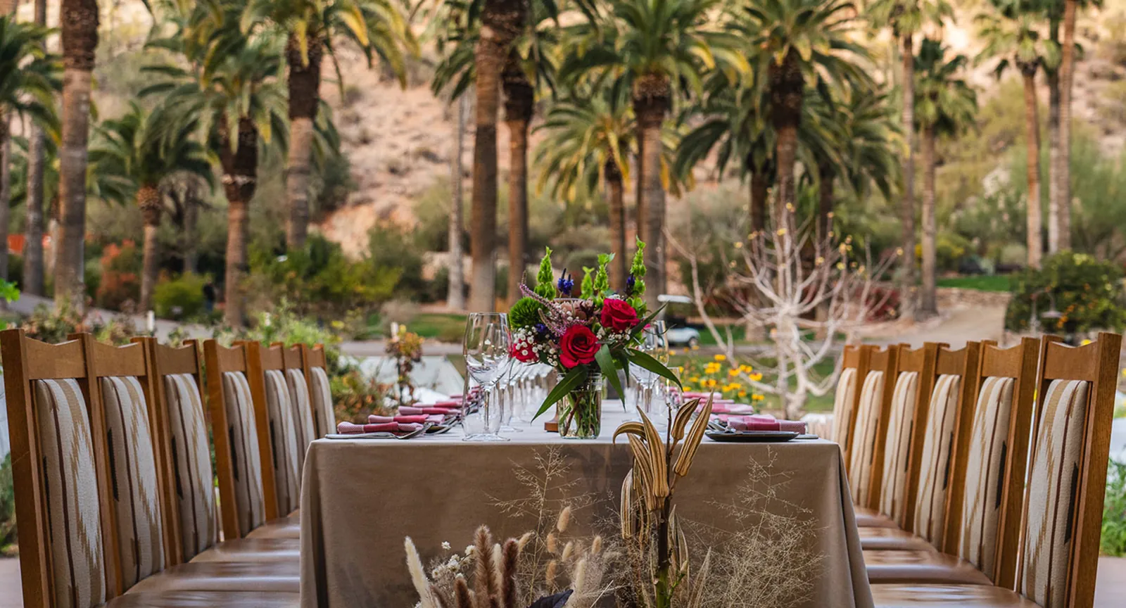 A beautifully set table among palm trees during the Sonoran Epicurean Escape culinary experience at Castle Hot Springs