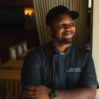Chef Quinton Beatty in a dark uniform with arms crossed at Castle Hot Springs restaurant.