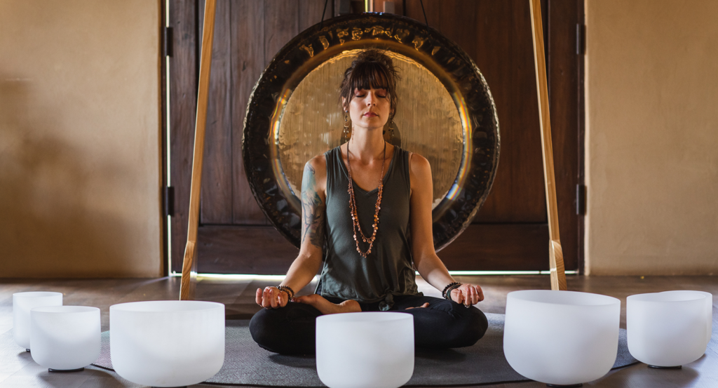 A woman meditating with a sound bath and bronze gong